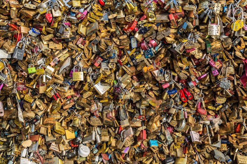 hundreds of padlocks with messages engraved or handwritten clustered so tightly on a fence that you can see nothing but padlocks