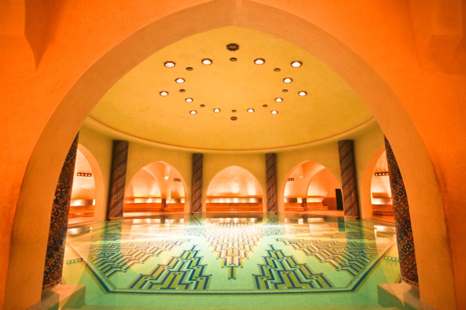 Luxury hamam with an octagonal shaped pool with blue tiled floor under a domed ceiling surrounded by a collonaded walkway in the Hassan II mosque in Casablanca, Morocco.