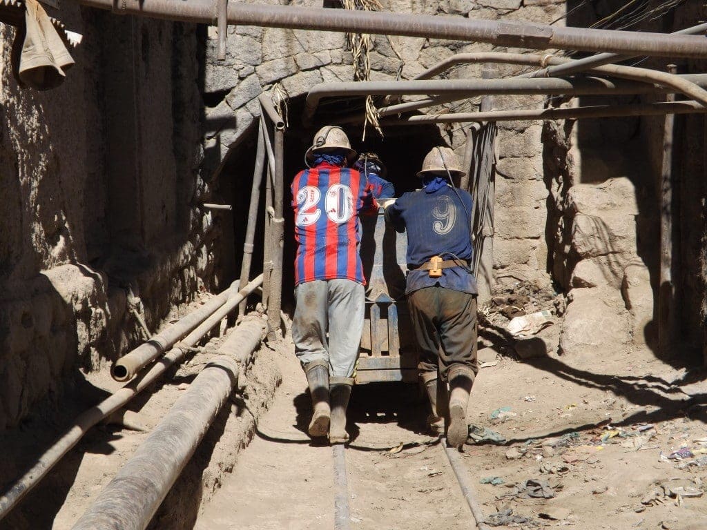 Miners pushing wagons by hand into the mine.