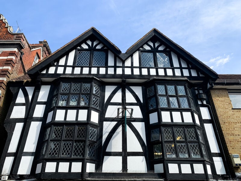white painted half timber tudor building with a black painted timber frame and double triangle roof