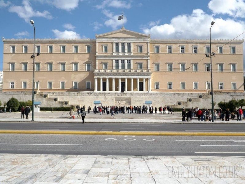Greek parliament in Athens, a large beige coloured palace in a neoclassical style with three storeys and a collonaded section around the main entrance