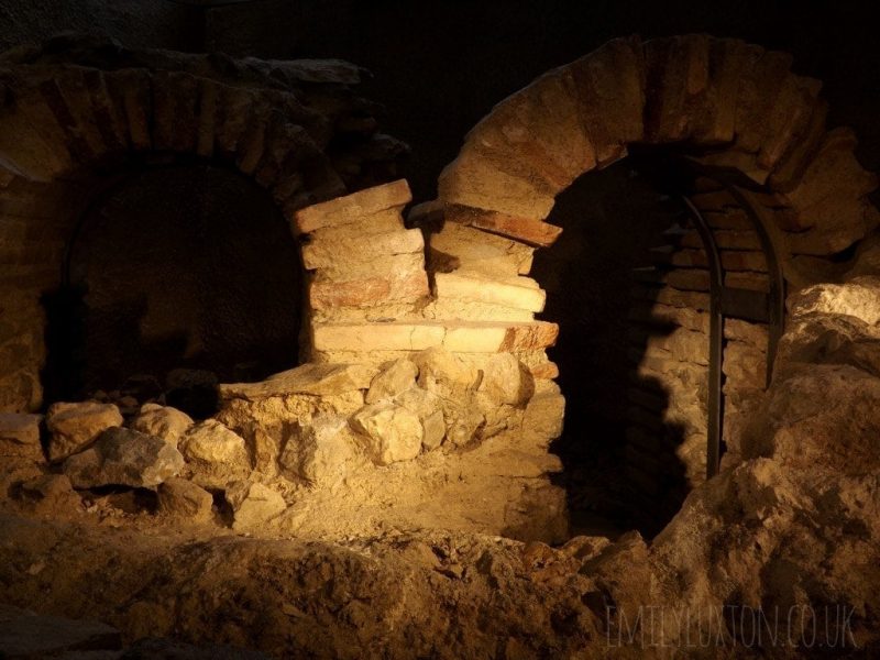 Ruins of an old roman tomb with two arches made of stacked pieces of limestone