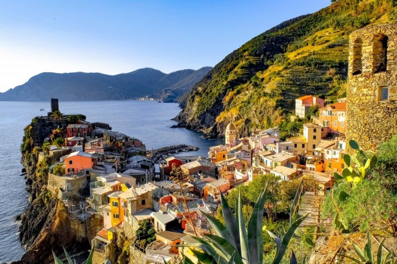 colourful houses on a narrow peninsula at sunset with the blue sea in the background