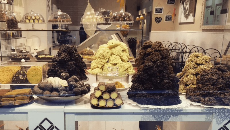 Window display in a chocolate shop in barcelona with large piles of white and brown chocolate truffles on a white wooden table 