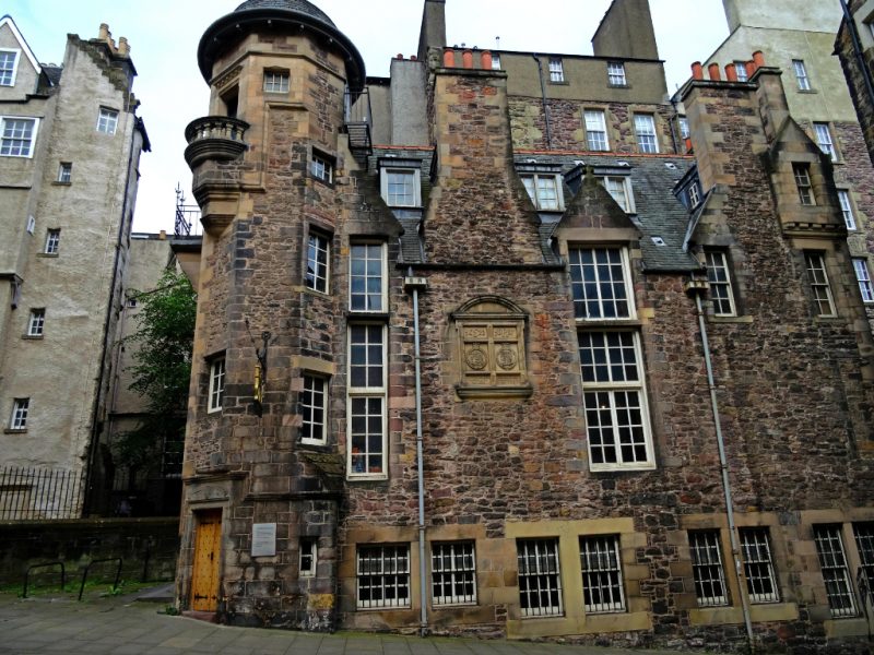 Exterior of the Writer's Museum in Scotland, a 5 or 6 storey historic looking building made from reddish light brown stone with grey slate tiled roof and an octagonal turret on the left side