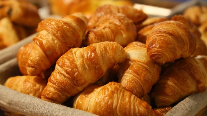 close up of a large pile of croissants in a cloth-lined basket