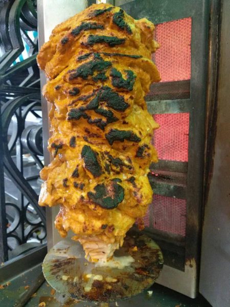 a roll of shawarma meat in a yellow-ish marinade cooking on a spit in Dubai