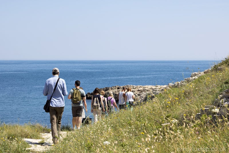 people walking in a line towards the coast on holiday in  puglia italy 