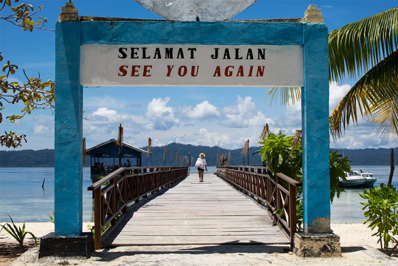 Girl in hat walking on pier under sign saying see you again