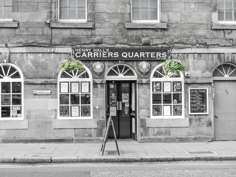 exterior of Henry Halls Carriers Quarters pub with grey stone walls and arched white framed windows