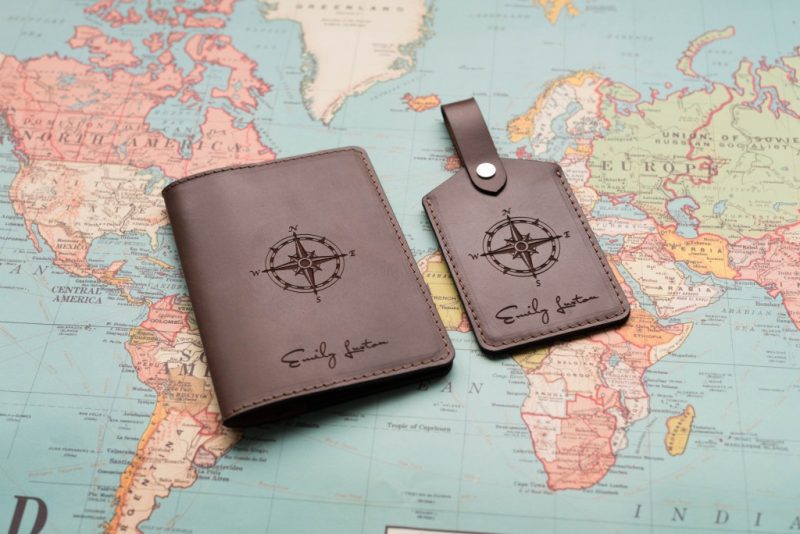 brown leather passport holder and luggage tag next to each other on a paper map, both are printed with a compass and the name Emily Luxton. Gift ideas for travel lovers