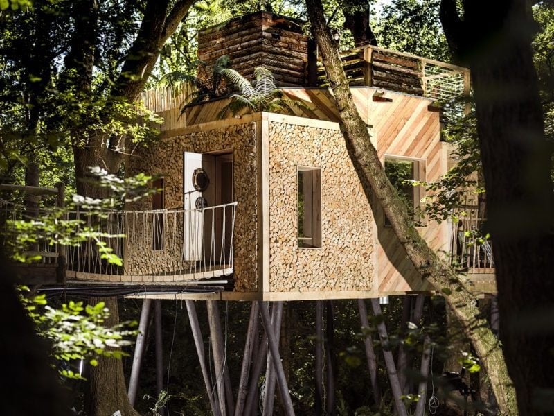 square wooden cabin on stilts surrounded by trees in a forest - unique places to stay Dorset