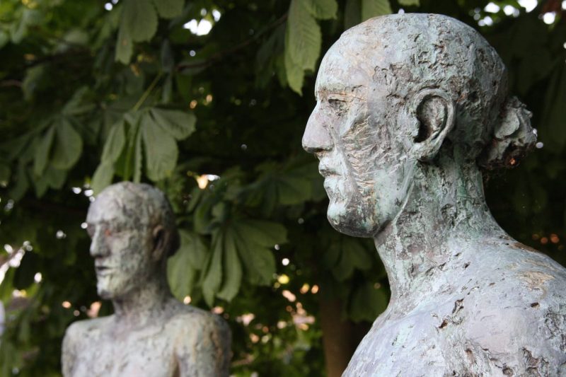 Close up of the head and shoulders of two bronze statues of men with roughly carved faces - the Dorset Tolpuddle Martyrs Statues in Dorchester