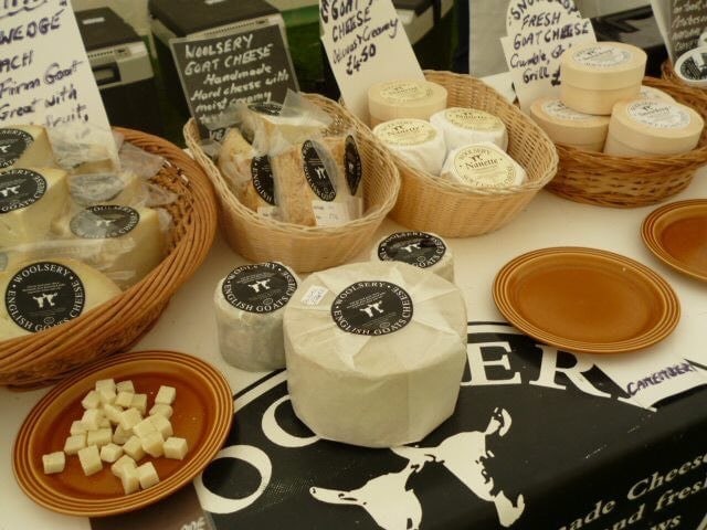 several small wicker baskets filled with wrapped circular cheeses on a trestle table