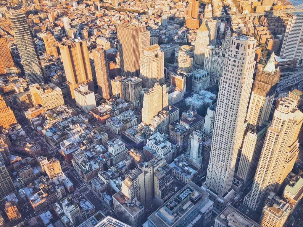 New York city viewed from above on a sunny day with sunlight shining on the many skyscrapers and buildings - cool things to do in NYC