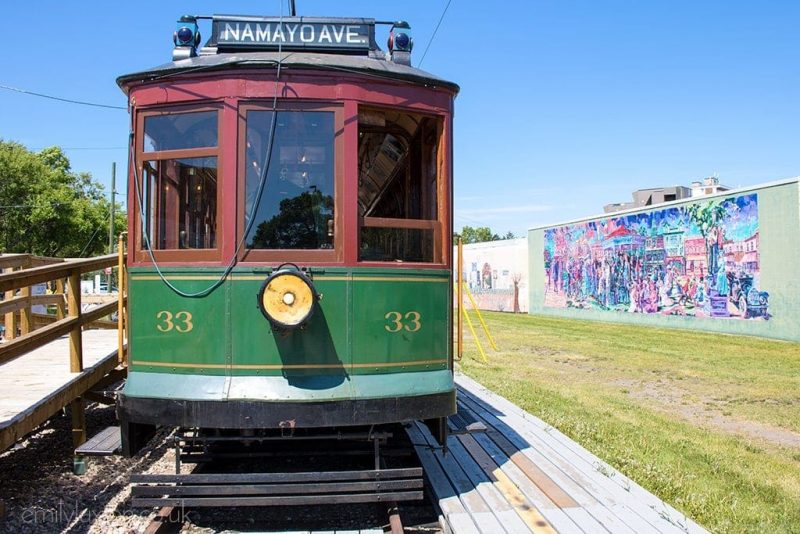 green tram with street art in background