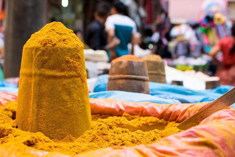 close up of a bowl of yellow spic with a small sandcastle style stack of the spice on top at a market in kathmandu nepal