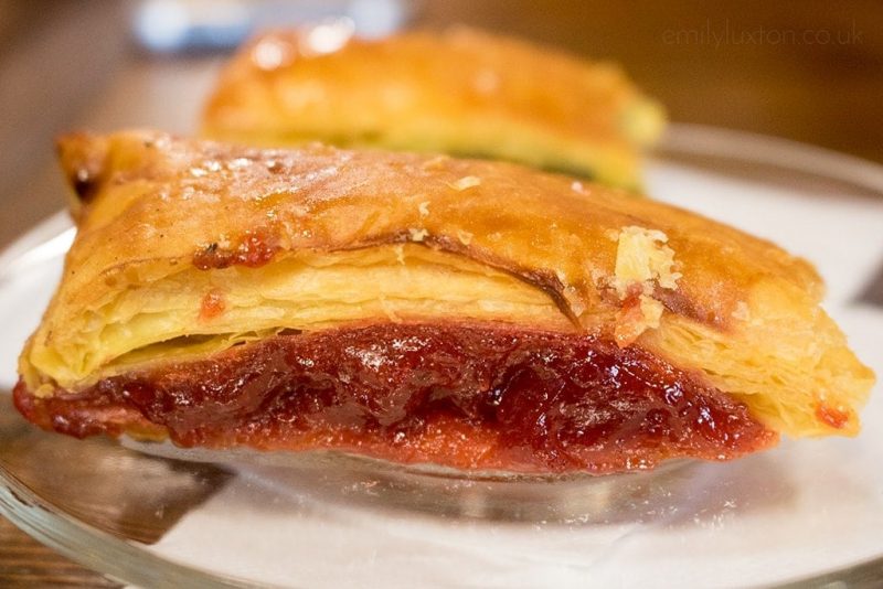 close up of a pastry with a red jam filling on a glass plate