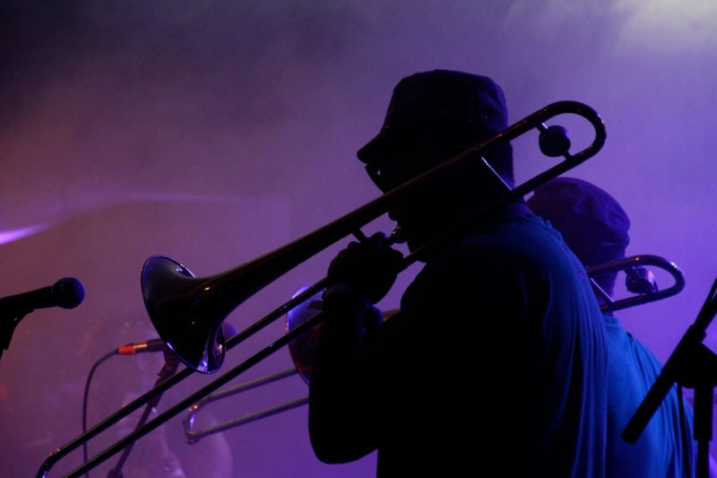 silhouette of a jazz musician playing trumpet in the French Quarter of New Orleans, Louisiana, with smoke and neon lights in the background.