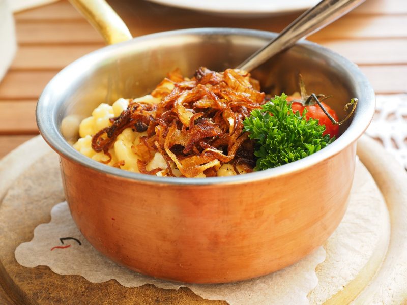 Tyrol Food Guide - copper pan full of dumplings and cheese topped with crispy onions