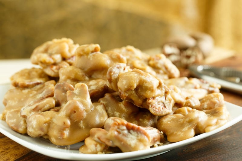 close up of a white plate filled with pale brown pecan pralines 
