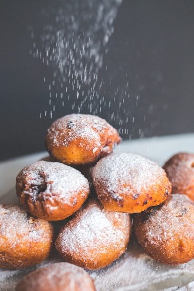 close up of small round balls of dough being dusted with white powder with a grey background