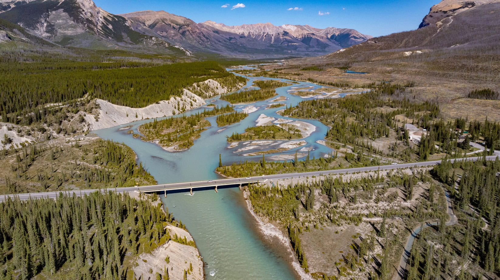 aerial landscape view of a road bridge crossing a river valley surrounded by forest and mountains