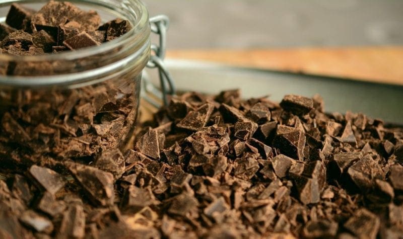close up of a glass jar filled with chocolate chips and surrounded by a pile of chocolate chips. Barcelona Chocolate Guide