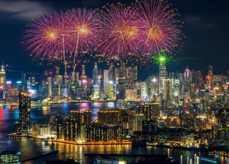 Chinese New Year Fireworks in the night sky above Beijing with the city skyline filled with hundreds of skyscrapers and tower blocks all lit up and reflected in the river. festivals around the world.