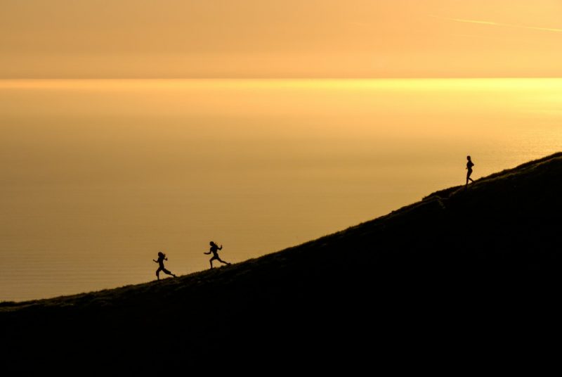 three women in silouette against a sunset on the sea running down a hill - Couch to 5K Review