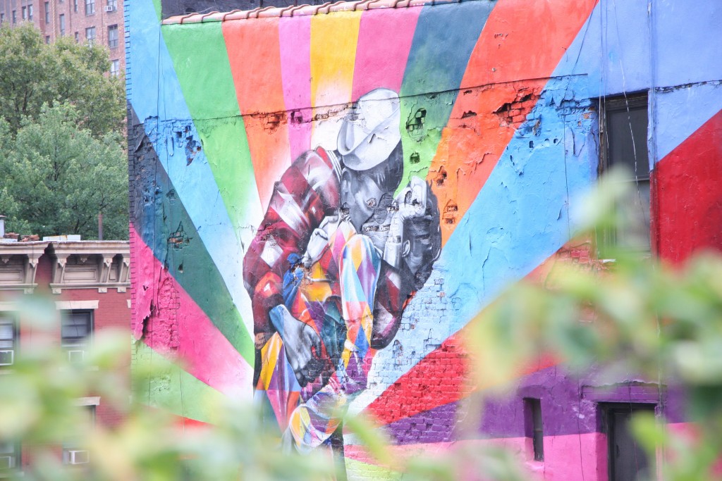 colourful street art mural in nyc with a black and white image of a couple kissing against a multicoloured background 