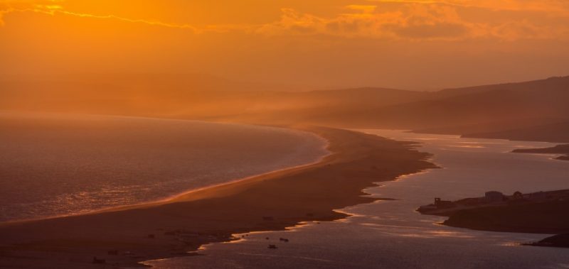 view of a long sandbank between the sea and a lagoon on the mainland taken at sunset with golden sky