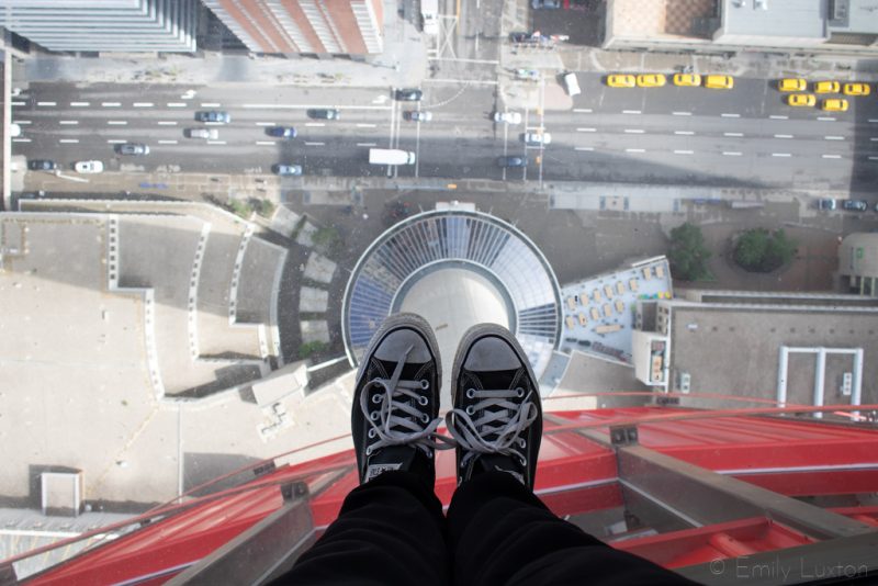 Converse shoes on a glass floor above a city street