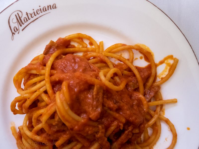 Flatlay of a white china plate with spaghetti and tomato sauce. 