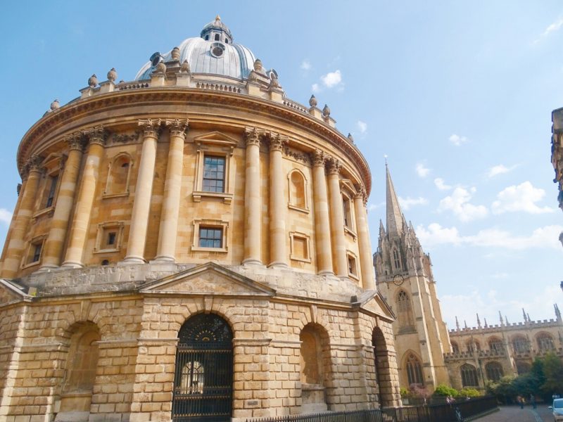 The circular building of Radcliffe Camera in Oxford England built from beige coloured stone and decorated with many pillars, with a domed grey roof, taken in Autumn