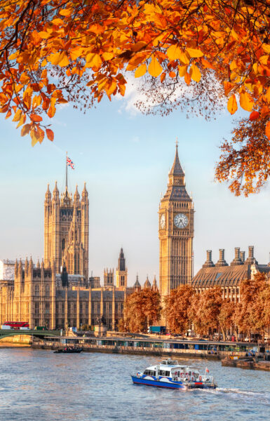 Big Ben, River Thames and the Houses of Parliament framed by orange autumn leaves in the foreground