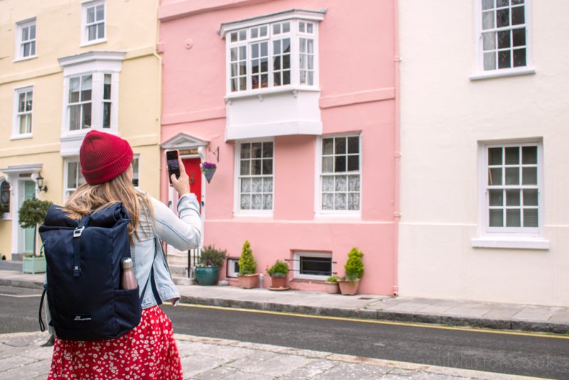 girl wearing backpack and taking photo on a phone