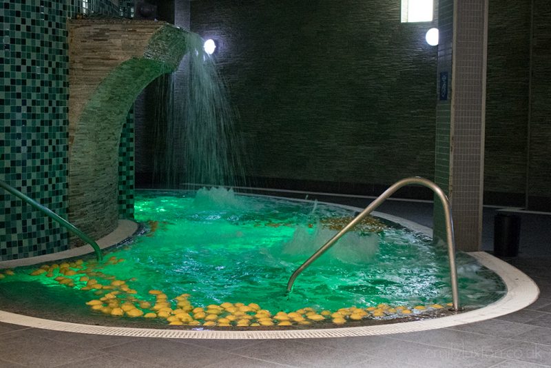 Hot tub inside a dimly lit room covered wiht grey tiles at a natural thermal spa in Spain