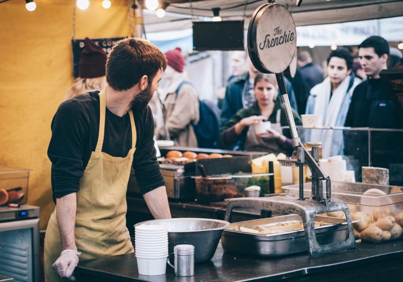 man serving at a market stall in London