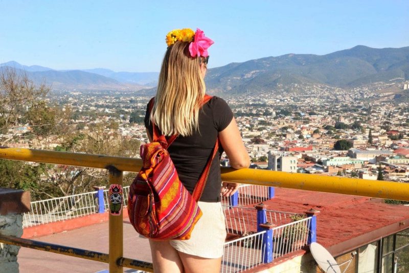 girl with blonde hair and flower headband wearing a red backpack  looking over Oaxaca city - Opodo Prime review
