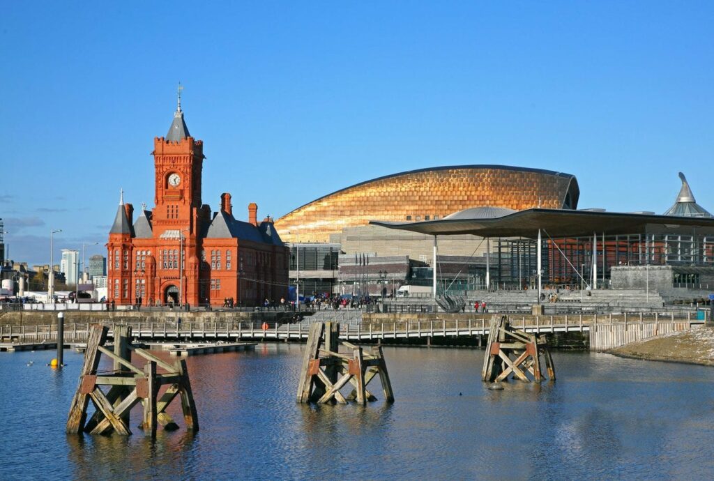 Looking across Cardiff Bay to a bridge, with a red brick building and large silver dome behind