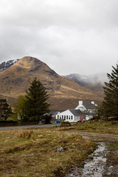 Black Sheep Hotels Cluanie Inn tucked between pine trees beneath a mountain