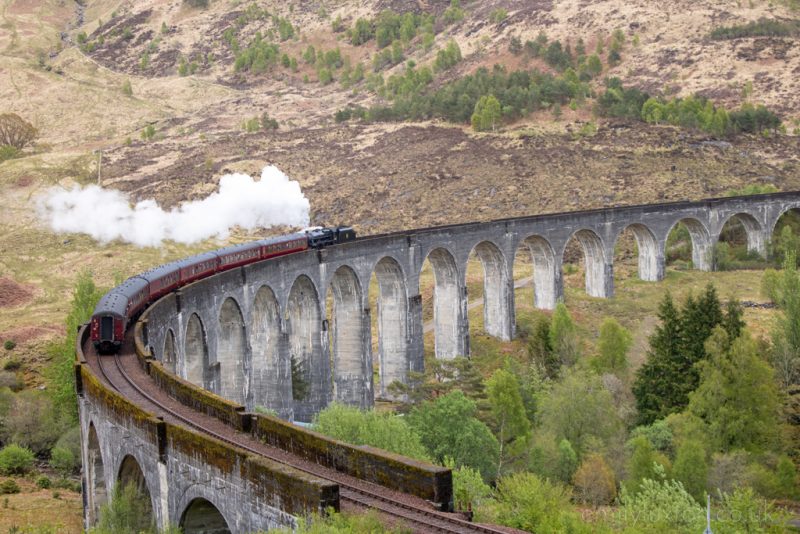 Steam train crossing the Harry Potter Viaduct in Scotland