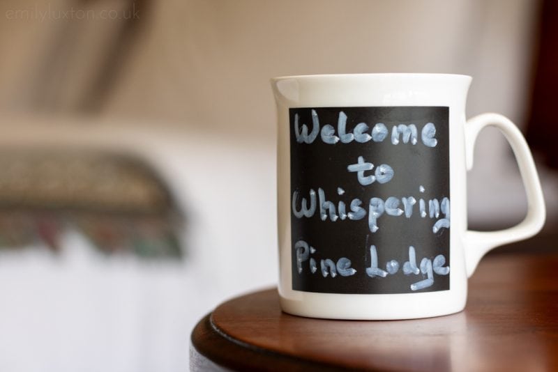 Black and white mug that reads Welcome to Whispering Pine Lodge 