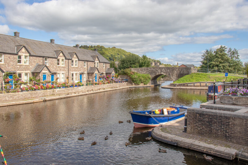 Terraced stone cottages next to a river with a blue rowing boat