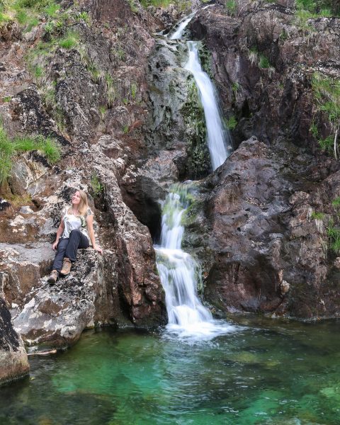 Emily sitting next to a waterfall near Dinas Emrys Snowdonia Wales