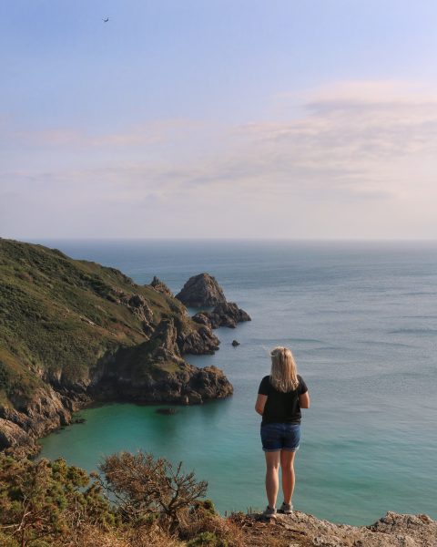 girl standing on a cliff at Petit Port in Guernsey - travel tips