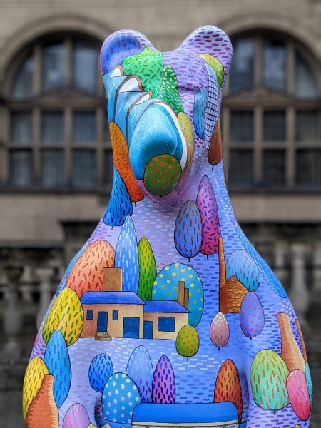 Bear painted purple with multicoloured trees and houses on it - part of the Sheffield Bears public art trail 