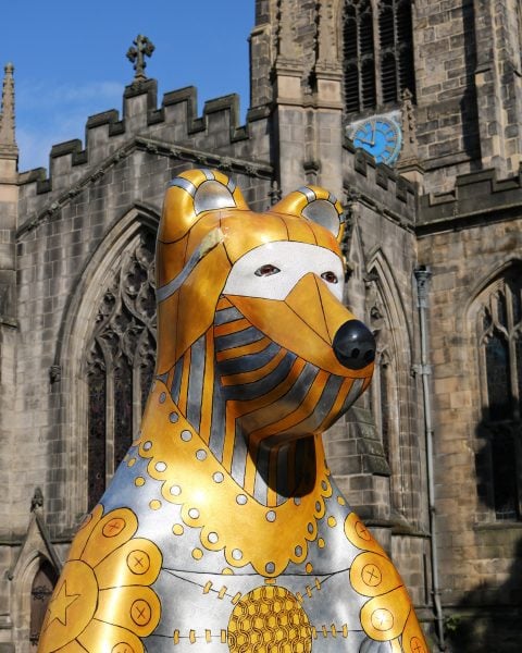 Gold and silver statue of a bear in front a cathedral - part of the heffield Bears public art trail