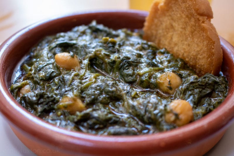 Close-up of stewed spinach with some chickpeas in a terracotta bowl